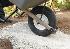 a man pushing a wheelbarrow on top of gravel