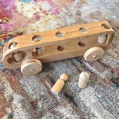 a wooden toy train sitting on top of a rug next to some wood pegs