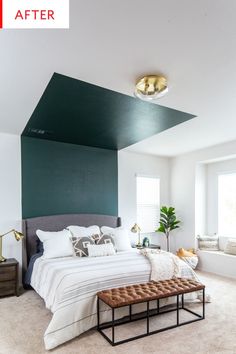 a bedroom with a large bed and green accent wall above the bed is a bench