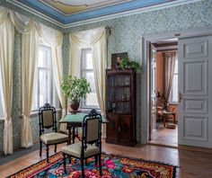 a living room filled with furniture next to two windows and a rug on top of a hard wood floor