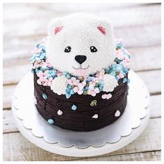 a cake decorated with flowers and a teddy bear on top is sitting on a plate