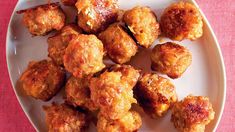 a white plate topped with meatballs on top of a pink tablecloth covered table