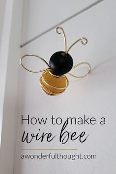 a bee hanging from the side of a door with text overlay that reads how to make a wire bee