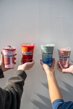 four people holding up three cups of ice cream