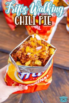 a person holding up a bag of chili pie