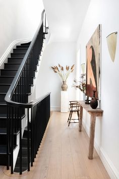 a black and white staircase leading up to a living room with a painting on the wall