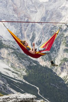 a woman laying in a hammock on top of a mountain