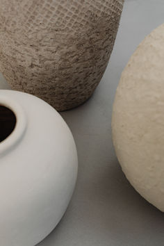 two white vases sitting next to each other on top of a table with a brown substance in the middle