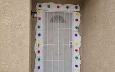 a decorated door on the side of a building that has a clock and multicolored balls all over it