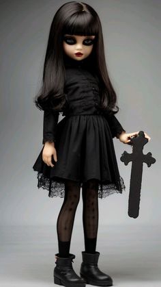 a doll dressed in black holding a cross