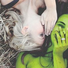 a woman laying on the ground next to a man with green paint painted on her body