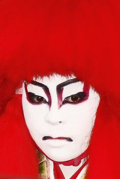 a close up of a person with red hair and white face paint wearing a costume