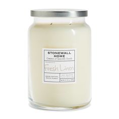 a glass jar filled with fresh linen scented candle on a white background, the label reads stonewall home