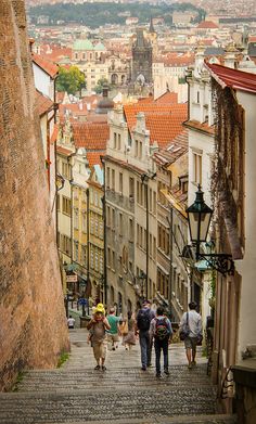 people walking up and down the stairs in an old city with tall buildings on either side