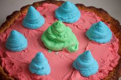 there is a cake with blue and pink frosting on the top, surrounded by small cupcakes