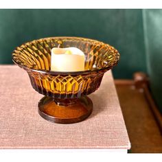 a candle sits in a glass bowl on a table