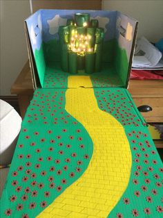 an open cardboard box with a yellow road going through it and lit candles in the middle