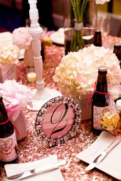 the table is set with flowers, wine bottles and napkins for guests to eat