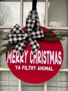 a merry christmas ya filthy animal sign hanging on a window sill with a bow