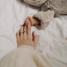 a woman is holding the hand of a stuffed elephant on a white bed with sheets