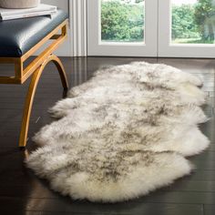 a sheepskin rug sitting on top of a hard wood floor next to a chair