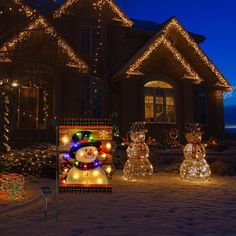 christmas lights decorate houses and lawns with snowmen in the front yard at night