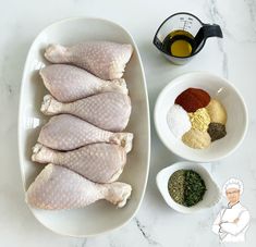 raw chicken with spices and seasonings in bowls on a white countertop next to a measuring cup