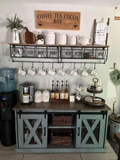 a coffee bar with cups and mugs on the shelves above it, along with other items