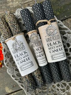 three black beeswax candles sitting on top of a metal tray next to an orange flower