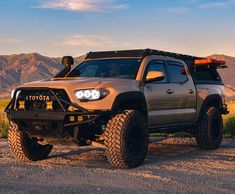 a silver truck parked on top of a dirt road