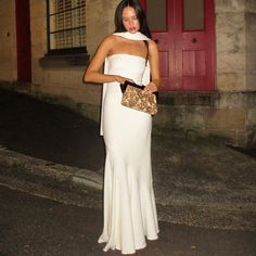 a woman in a white dress holding a purse