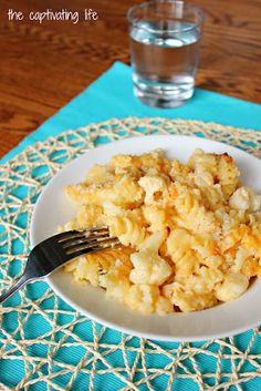 a white plate topped with macaroni and cheese next to a glass of water