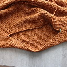 an orange knitted blanket sitting on top of a wooden floor