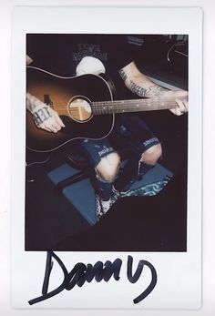 a man sitting down with a guitar in his hand