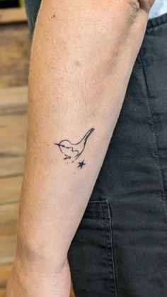 a man's arm with a small bird tattoo on the left side of his arm