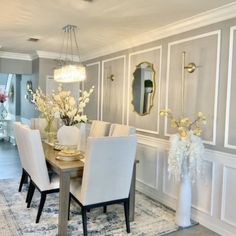 a dining room table with white chairs and flowers