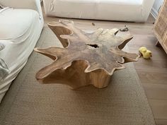 a wooden table sitting on top of a carpeted floor next to a white couch