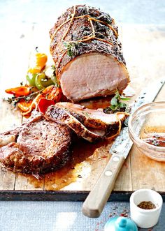 a large piece of meat sitting on top of a cutting board next to a knife