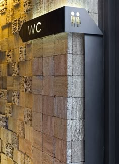 the corner of a building with a sign on it that says w c and is lit up at night