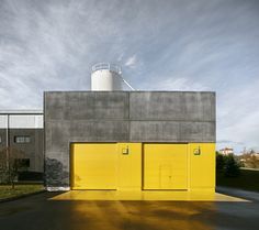 two yellow doors are in front of a gray building with a silo on top