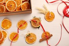 orange slices cut in half and tied with red ribbon next to a box of cinnamons