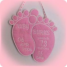 two pink baby feet ornament hanging on a wall