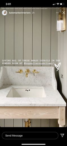 a bathroom vanity with marble counter top and gold faucet fixtures on the wall