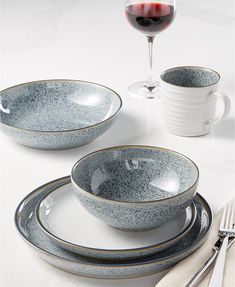 a white table topped with plates and bowls filled with food next to a glass of wine