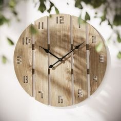 a wooden clock hanging from the side of a wall with numbers on it's face