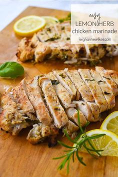 sliced up chicken on a cutting board with lemons and herbs next to the meat