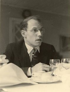 an old black and white photo of a man sitting at a table with wine glasses