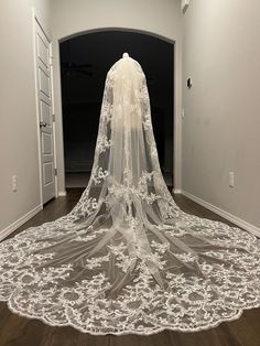 a white wedding veil on top of a wooden floor in an empty room with doors