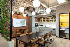 an office with tables, chairs and plants on the wall