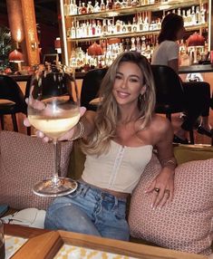 a woman sitting at a table with a glass of wine in front of her on the couch